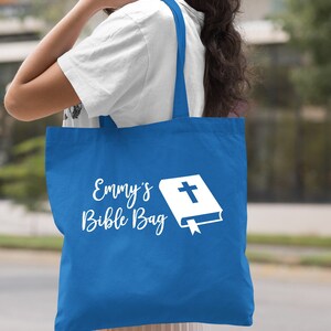 May include: A royal blue tote bag with white text that says "Emmy's Bible Bag" and a white image of a closed book with a cross on the cover.
