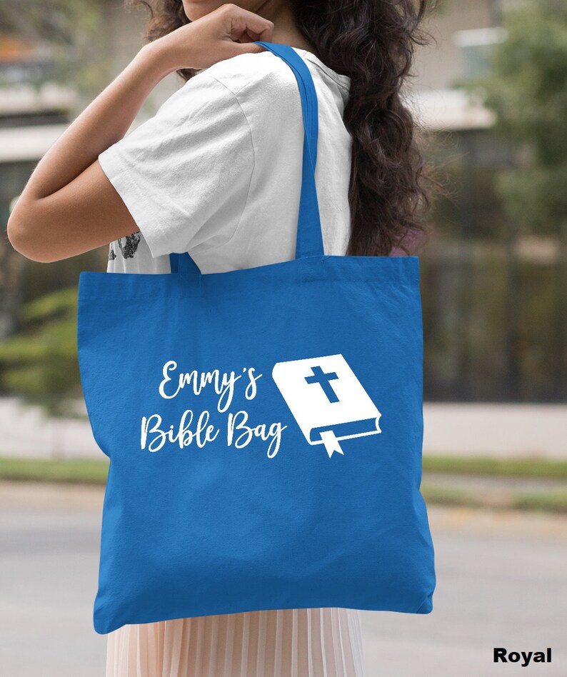 May include: A royal blue tote bag with white text that says "Emmy's Bible Bag" and a white image of a closed book with a cross on the cover.