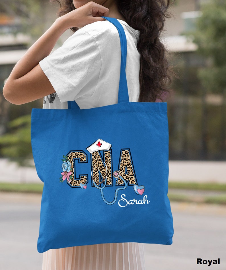 May include: A royal blue tote bag with a leopard print design that says "CNA" with a stethoscope and a nurse's hat. The name "Sarah" is written below the design.