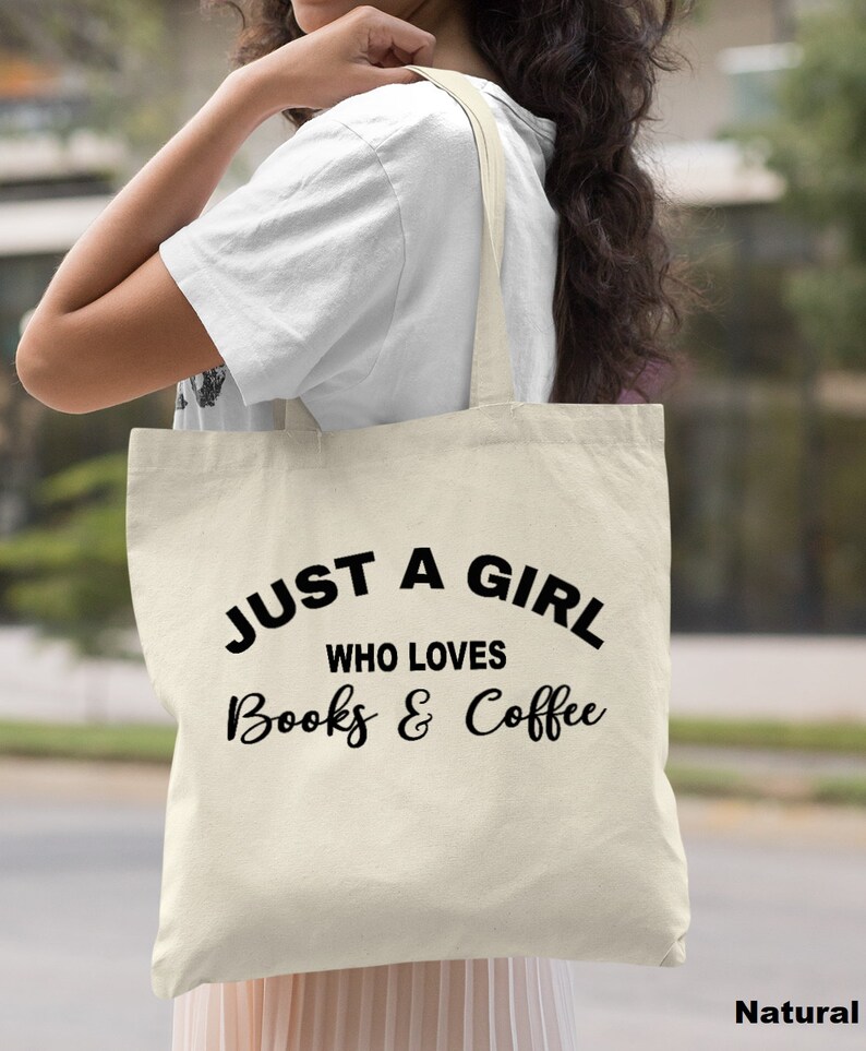 Puede incluir: Una bolsa de tela de lona natural con texto negro que dice "Just a girl who loves books & coffee".
