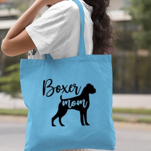Puede incluir: Bolsa de tela azul claro con texto negro y una silueta negra de un perro boxer. El texto dice "Boxer mom".