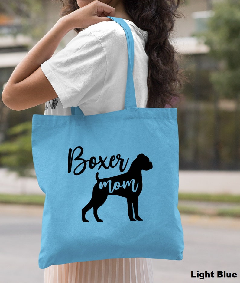 Puede incluir: Bolsa de tela azul claro con texto negro y una silueta negra de un perro boxer. El texto dice "Boxer mom".