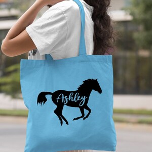 May include: Light blue tote bag with a black silhouette of a horse and the name "Ashley" written in cursive.