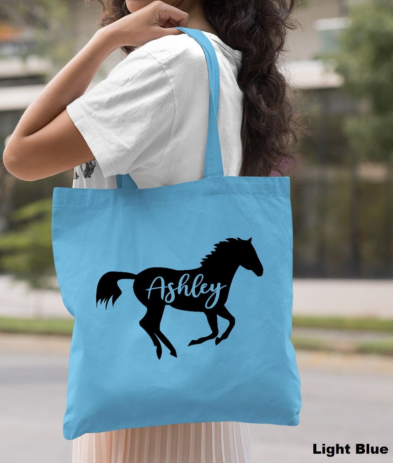 May include: Light blue tote bag with a black silhouette of a horse and the name "Ashley" written in cursive.