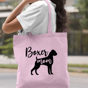 Puede incluir: Bolsa de tela de lona rosa claro con una silueta negra de un perro boxer y el texto "Boxer mom".