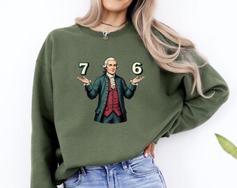 May include: Olive green sweatshirt featuring a graphic of a historical figure holding the numbers 7 and 6. The figure is dressed in a green coat, red vest, and white shirt. The sweatshirt is a casual style.