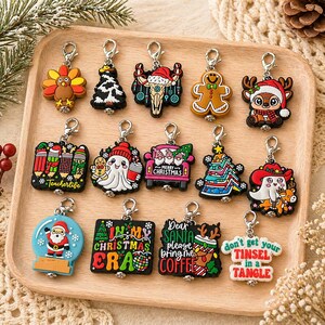 May include: A collection of Christmas-themed keychains with various designs, including a turkey, Christmas tree, gingerbread man, and Santa Claus. Some keychains have text like "Teacherlife" and "Dear Santa please bring me coffee."