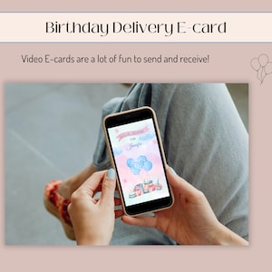 K&ouml;nnte beinhalten: Eine Person h&auml;lt ein Smartphone, auf dem eine Geburtstags-E-Card mit einem blauen und rosafarbenen Aquarellhintergrund, Ballons und dem Text "Happy Birthday for Ja" angezeigt wird.