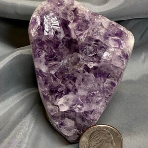 May include: A large amethyst geode with a purple and white crystal formation. The geode is about the size of a half dollar.