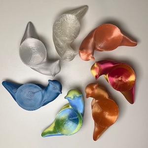Puede incluir: Seis hueveras de cerámica en varios colores, incluyendo azul, verde, rojo, blanco y marrón. Cada huevera tiene un diseño único y está en forma de pájaro.