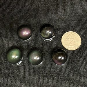 May include: Six iridescent black obsidian spheres with a rainbow sheen. The spheres are approximately the size of a US quarter.