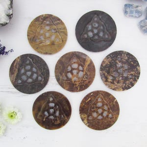 May include: Seven round coasters with a brown, mottled appearance. Each coaster features a raised, triangular design with a pattern of small, light-colored shapes. The coasters are arranged on a white surface, suggesting a decorative or functional item.