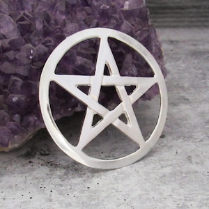 May include: A silver pentacle pendant with a five-pointed star design. The pendant is round and has a smooth, polished finish.
