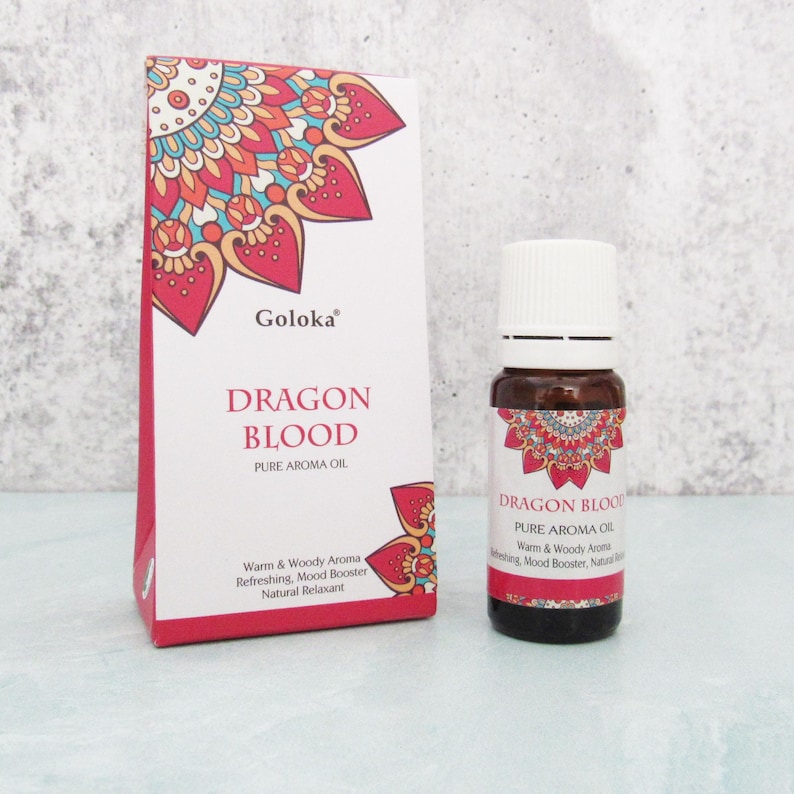 K&ouml;nnte beinhalten: Eine kleine Flasche mit reinem Dragon Blood Aroma&ouml;l mit einem roten und wei&szlig;en Mandala-Design-Etikett. Die Flasche steht auf einer wei&szlig;en Oberfl&auml;che. Der Text auf dem Etikett lautet "Goloka Dragon Blood Pure Aroma Oil Warm & Woody Aroma Refreshing, Mood Booster Natural Relaxant"