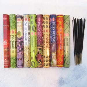 May include: Assortment of 11 different incense sticks with various scents, including sandalwood, patchouli, white sage, and dragon's blood. The incense sticks are packaged in colorful boxes with text and images. A bundle of black incense sticks is also included.