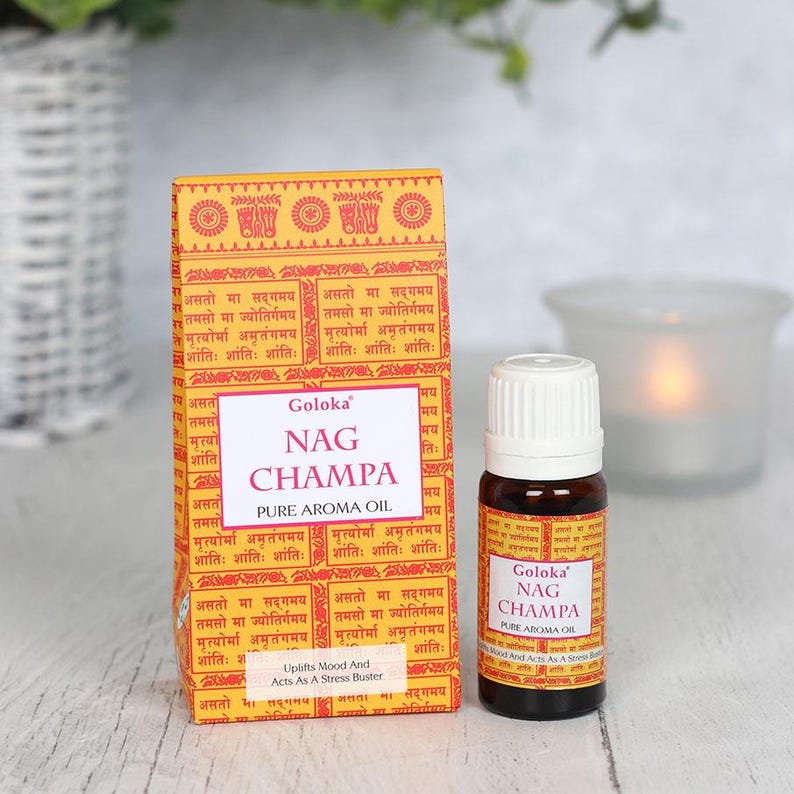 K&ouml;nnte beinhalten: Eine gelbe Schachtel mit Sanskrit-Text und den Worten "Goloka Nag Champa Pure Aroma Oil" darauf. Eine kleine braune Glasflasche mit wei&szlig;em Verschluss und dem gleichen Text auf dem Etikett. Die Flasche steht auf einer hellen Holzoberfl&auml;che.