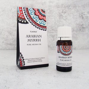 K&ouml;nnte beinhalten: Eine kleine braune Glasflasche mit wei&szlig;em Verschluss, beschriftet mit "Arabian Myrrh Pure Aroma Oil". Die Flasche steht auf einer wei&szlig;en Oberfl&auml;che, hinter ihr befindet sich eine farbenfrohe Schachtel mit Muster. Die Schachtel ist mit "Goloka Arabian Myrrh Pure Aroma Oil" beschriftet und enth&auml;lt eine Beschreibung der Vorteile des &Ouml;ls.