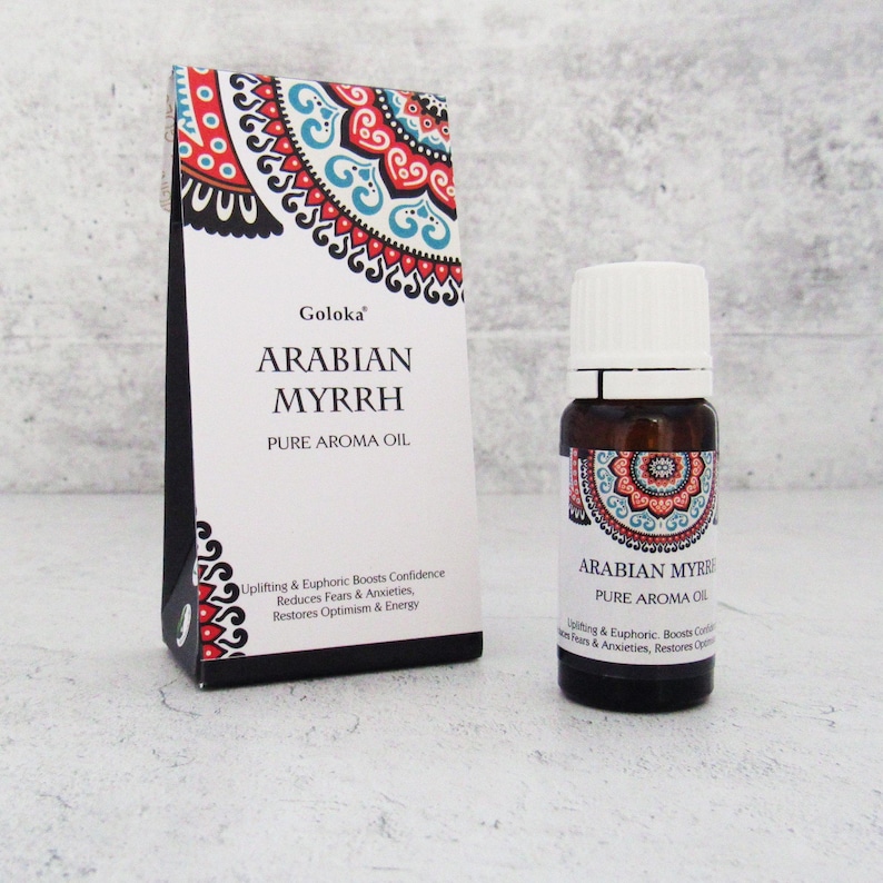 K&ouml;nnte beinhalten: Eine kleine braune Glasflasche mit wei&szlig;em Verschluss, beschriftet mit "Arabian Myrrh Pure Aroma Oil". Die Flasche steht auf einer wei&szlig;en Oberfl&auml;che, hinter ihr befindet sich eine farbenfrohe Schachtel mit Muster. Die Schachtel ist mit "Goloka Arabian Myrrh Pure Aroma Oil" beschriftet und enth&auml;lt eine Beschreibung der Vorteile des &Ouml;ls.