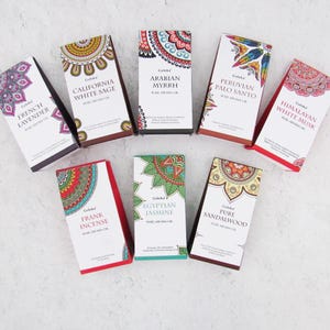 May include: A set of ten small, colourful boxes with intricate mandala designs. Each box contains a pure aroma oil with a different scent, including French Lavender, California White Sage, Arabian Myrrh, Peruvian Palo Santo, Himalayan White Musk, Frank Incense, Egyptian Jasmine, and Pure Sandalwood.