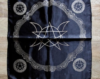 Può includere: Sciarpa di seta nera con un pentagramma bianco e un motivo di luna tripla. Il design è circondato da un bordo decorativo.