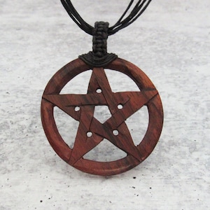 May include: A wooden pendant necklace with a dark red pentagram design. The necklace is made of black cord.