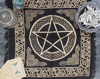 Può includere: Tovaglia da altare nera con un pentagramma dorato e un bordo di nodo celtico. La tovaglia è frangiata e ha un design decorativo negli angoli.