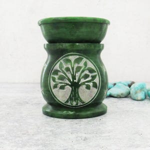 Könnte beinhalten: Grüner Stein-Ölbrenner mit einem geschnitzten Lebensbaum-Design. Der Brenner besteht aus zwei Teilen, einer oberen Schale für Wachs-Schmelzen und einer unteren Basis mit einem Teelicht-Halter.
