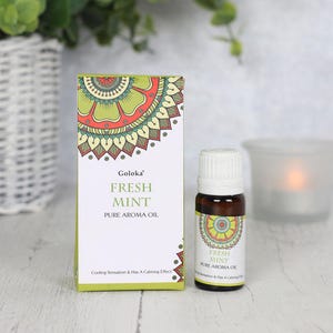 K&ouml;nnte beinhalten: Eine kleine Flasche Goloka Fresh Mint Pure Aroma Oil. Die Flasche ist aus braunem Glas mit einem wei&szlig;en Verschluss und einem Etikett mit einem gr&uuml;nen und roten Mandala-Design. Das Etikett tr&auml;gt die Aufschrift "Goloka Fresh Mint Pure Aroma Oil" und "Cooling Sensation & Has A Calming Effect".