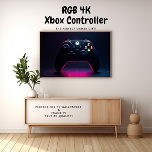 May include: A framed image of an Xbox controller with RGB 4K resolution. The controller is black with colorful buttons and a glowing pink base. Text at the top reads "RGB 4K Xbox Controller". Additional text states "PERFECT FOR PC WALLPAPERS & FRAME TV TRUE 4K QUALITY!"