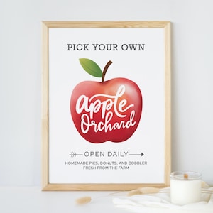 Puede incluir: Un cartel con una ilustración de una manzana roja y el texto "PICK YOUR OWN apple Orchard" y "OPEN DAILY - HOMEMADE PIES, DONUTS, AND COBBLER FRESH FROM THE FARM".