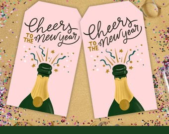 May include: Two pink printable gift tags with a champagne bottle popping with gold confetti and the text "Cheers to the New Year".