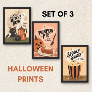 Può includere: Un set di tre stampe incorniciate a tema Halloween. La prima stampa mostra un gatto nero, una caffettiera e il testo Witch's Brew Served Daily. La seconda mostra una zucca, una fetta di torta e Pumpkin Pie A Slice of Magic. La terza mostra popcorn e Spooky Snacks So Good It's Scary.
