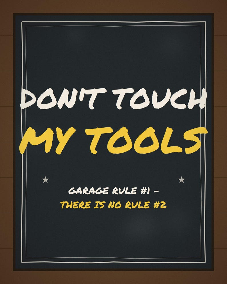Pu&ograve; includere: Un cartello rettangolare nero con bordo bianco che presenta il testo DON'T TOUCH MY TOOLS in bianco e giallo, seguito dal testo GARAGE RULE #1 - THERE IS NO RULE #2 in giallo, accentuato da due piccole stelle bianche su entrambi i lati.