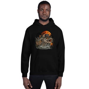 K&ouml;nnte beinhalten: Ein schwarzer Kapuzenpullover mit einer Grafik eines skelettierten Fisches mit Baseballkappe, der aus dem Wasser auftaucht. Das Design zeigt ein Holzschild mit der Aufschrift "BAD THINGS BITE", einen orangefarbenen Mond, Flederm&auml;use und einen K&uuml;rbis.