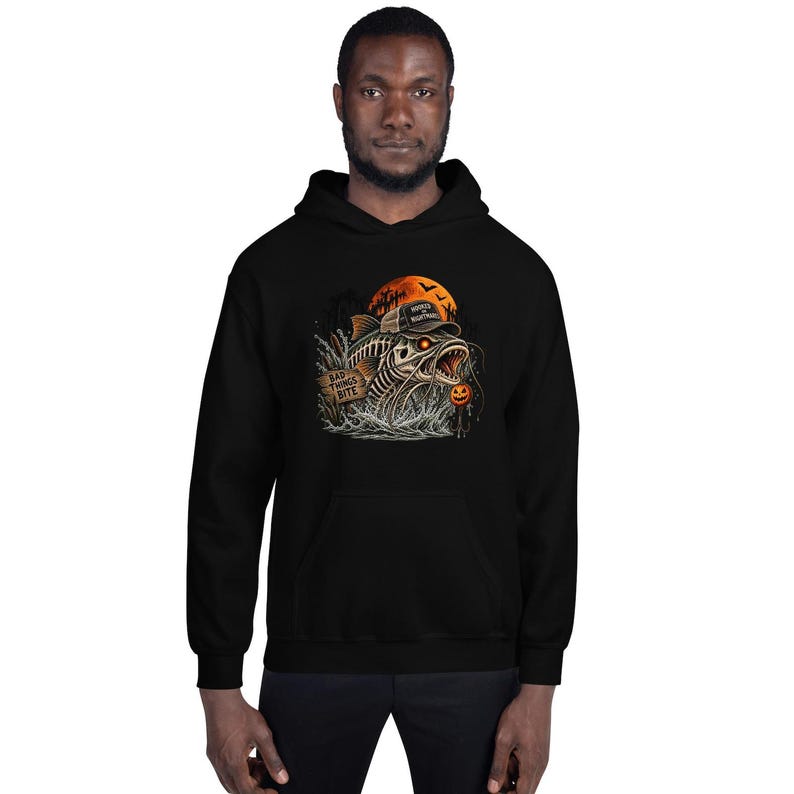 K&ouml;nnte beinhalten: Ein schwarzer Kapuzenpullover mit einer Grafik eines skelettierten Fisches mit Baseballkappe, der aus dem Wasser auftaucht. Das Design zeigt ein Holzschild mit der Aufschrift "BAD THINGS BITE", einen orangefarbenen Mond, Flederm&auml;use und einen K&uuml;rbis.