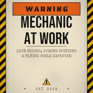 Pu&ograve; includere: Un cartello rettangolare con un bordo a strisce diagonali gialle e nere. Il testo recita WARNING MECHANIC AT WORK, LOUD NOISES, STRONG OPINIONS & FLYING TOOLS EXPECTED e EST. 2026. Presenta un'intestazione arancione e un piccolo triangolo di avviso.