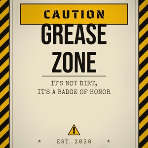 Pu&ograve; includere: Un cartello rettangolare con un bordo a strisce diagonali gialle e nere. Il testo recita CAUTION GREASE ZONE, IT'S NOT DIRT, IT'S A BADGE OF HONOR e EST. 2026. Un triangolo giallo con un punto esclamativo &egrave; centrato sopra l'anno.
