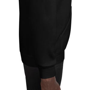 K&ouml;nnte beinhalten: Ein einfarbiger, schwarzer Kapuzenpullover mit langen &Auml;rmeln, einer K&auml;ngurutasche auf der Vorderseite sowie gerippten B&uuml;ndchen an &Auml;rmeln und Saum. Das Kleidungsst&uuml;ck besteht aus einem glatten, blickdichten Stoff und ist im Seitenprofil zu sehen.