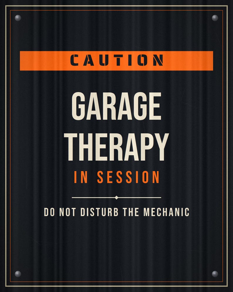 Pu&ograve; includere: Una targa rettangolare in metallo nero con una texture ondulata e quattro rivetti argentati agli angoli. La targa presenta un testo arancione e crema che recita: CAUTION GARAGE THERAPY IN SESSION DO NOT DISTURB THE MECHANIC, incorniciato da un sottile bordo arancione.