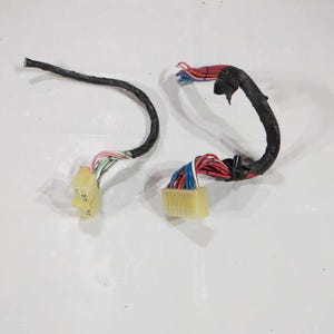 May include: Two automotive wiring harnesses. Each harness has a black, curved, insulated wire bundle with multiple colored wires extending from a beige connector. The wires are red, blue, white, pink, and green.