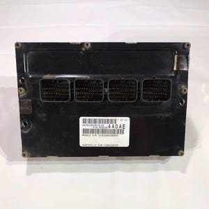 May include: A black electronic control module with multiple connector ports. A white label displays text including "DAIMLERCHRYSLER" and "440AE". The module has several screw holes and is likely for automotive use.