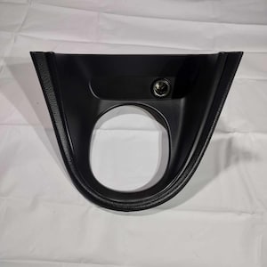 May include: Black plastic car interior trim piece with a cigarette lighter socket.