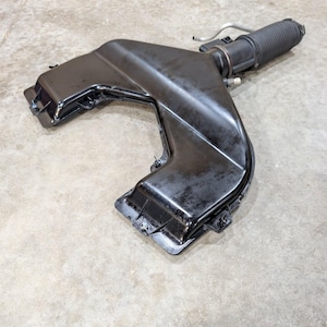 May include: A black automotive air intake duct assembly featuring a wide, flat, Y-shaped plastic housing connected to a cylindrical, ribbed flexible hose section with a small metal tube extending from the side of the connector piece.