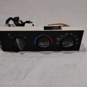 May include: Black and white car climate control panel with knobs for fan speed, temperature, and air conditioning. The panel has labels for "LO", "HI", "MAX A/C", "OFF", and "A/C".