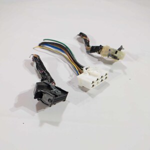 Könnte beinhalten: Drei elektrische Steckverbinder für Kraftfahrzeuge mit mehrfarbigen Drähten. Ein Stecker ist schwarz, ein anderer weiß und der dritte hellbraun. Die Drähte sind mit schwarzem Klebeband gebündelt.