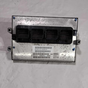 May include: A silver automotive control module with four black connectors and a label that reads "MOTOROLA S/N 5604000001995", "AUTHORIZED SOFTWARE UPDATE", "56023 039AG", "SEQUENCE #", "5R0AA", "517110".