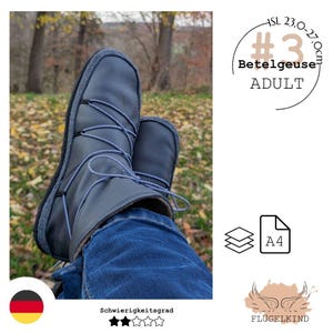 Könnte beinhalten: Ein Paar dunkelgraue Lederstiefeletten mit Kreuzschnürung und dünnen blau-weiß gemusterten Schnürsenkeln. Die Stiefel sind als Betelgeuse Adult mit einem Größenbereich von 23,0-27,0 cm gekennzeichnet und enthalten ein A4-Schnittmuster-Symbol.