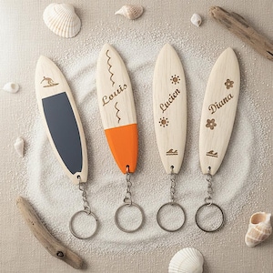May include: Four wooden surfboard keyrings with engraved names and designs. One has a surfer graphic and a dark blue section. Another has the name "Louis" and orange paint. The others have the names "Lucien" and "Diana".