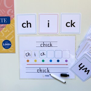 May include: A white dry-erase board with the word "chick" written on it. There are three cards with the letters "ch", "i", and "ck" on them. There are also colorful dots and a dry-erase marker.