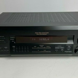 Puede incluir: Receptor estéreo FM Sony STR-DE325 negro. La pantalla digital muestra "FM 98.90 A". Cuenta con una perilla de volumen principal, botones de función y opciones de entrada. La parte superior tiene un diseño texturizado. Componente de audio doméstico.
